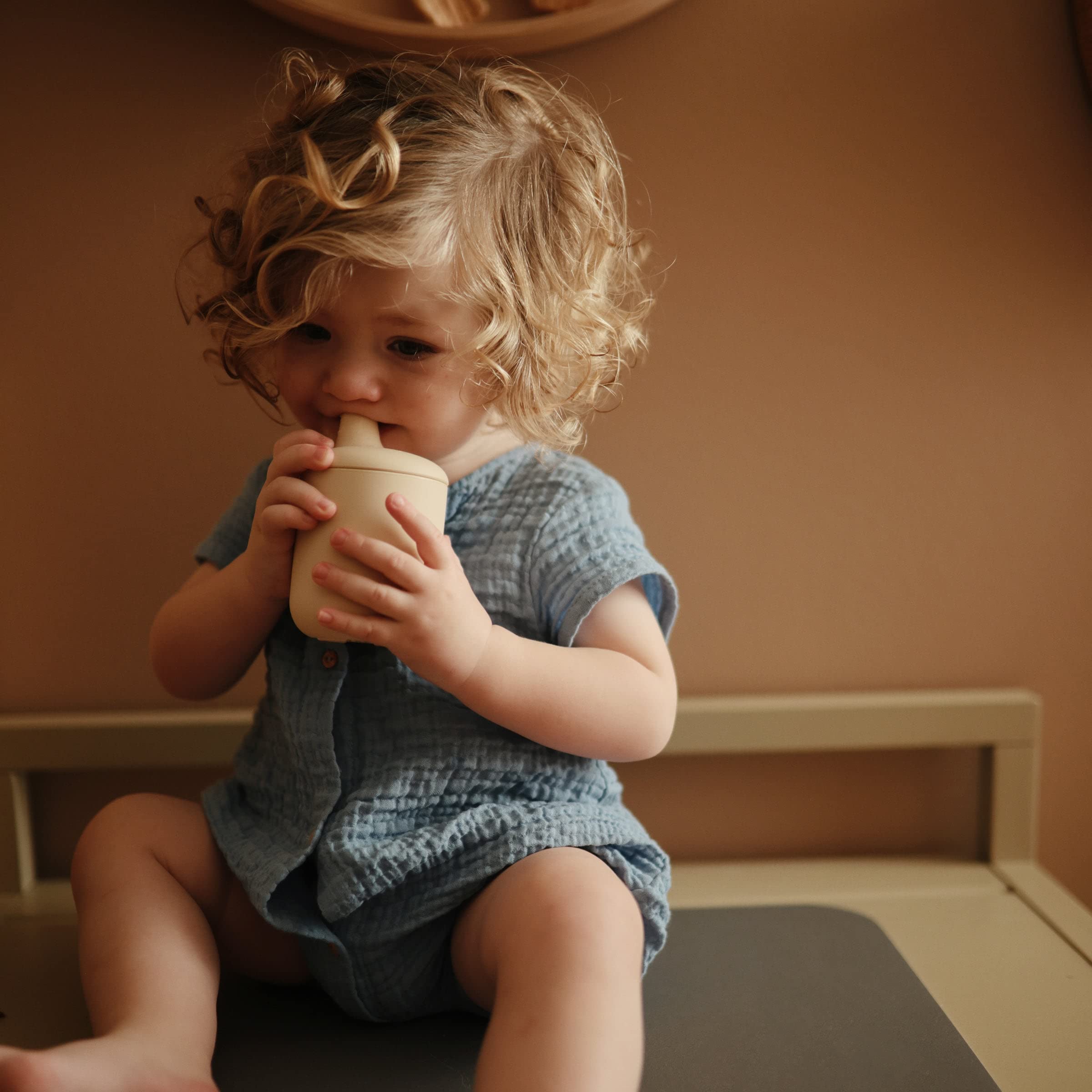 Mushie sippy cup baby-holding demonstrates comfortable grip for tiny hands