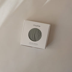 Mushie Stretchy Swaddle Blanket wrapped around baby demonstrates secure, snug wrap.