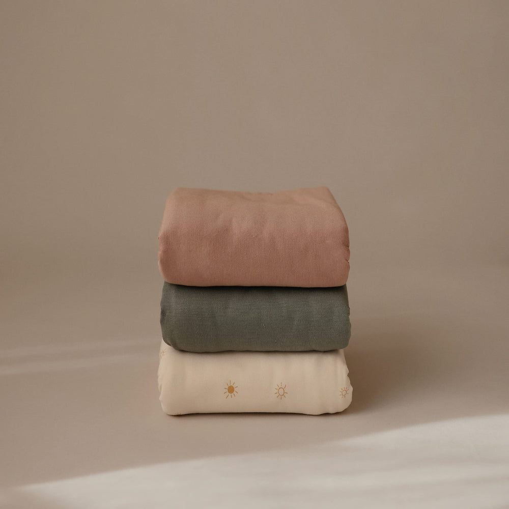 Mushie stretchy swaddle natural stretched fabric detail shows flexibility.