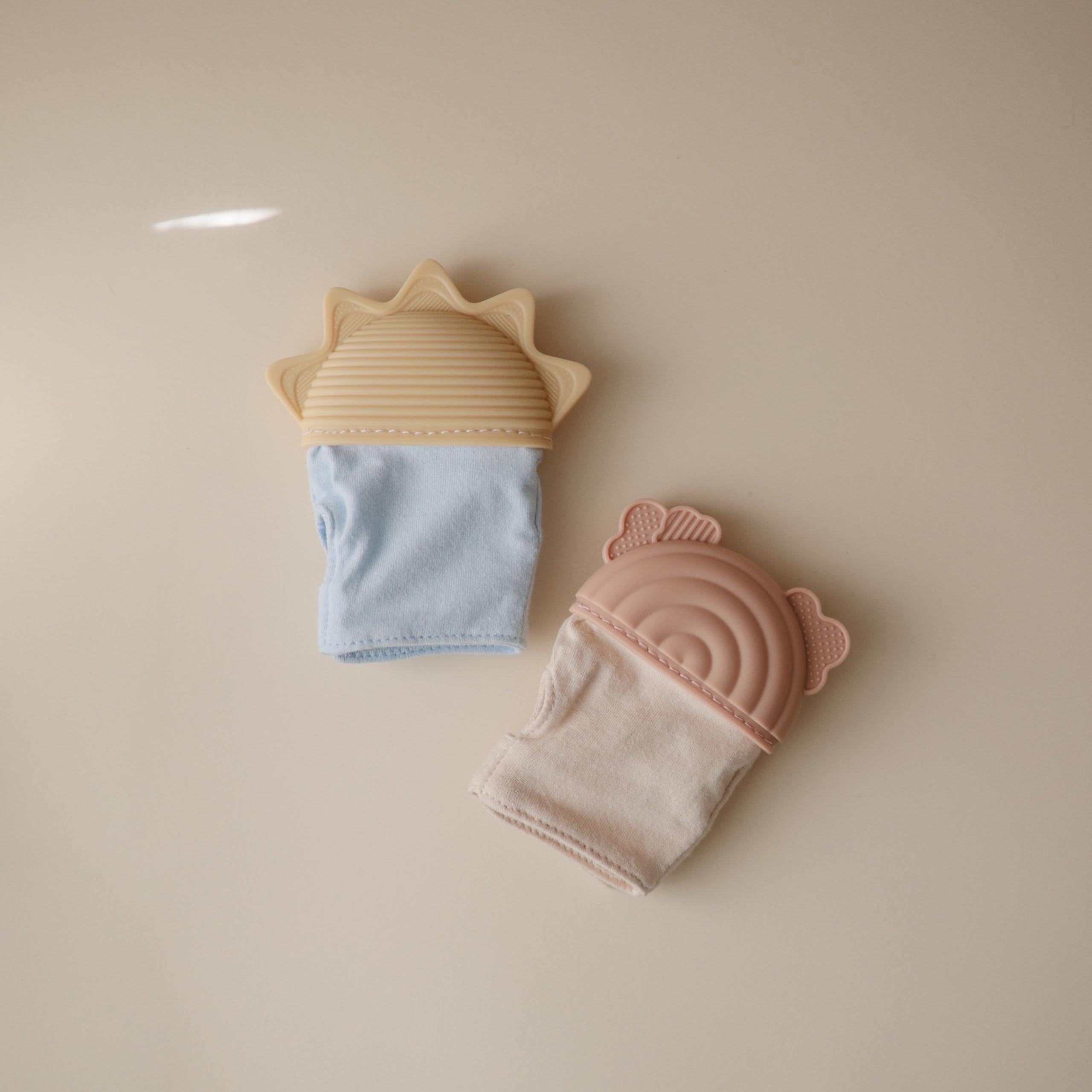 Mushie teething mitten rainbow in-use shot suggests calming teething routines.