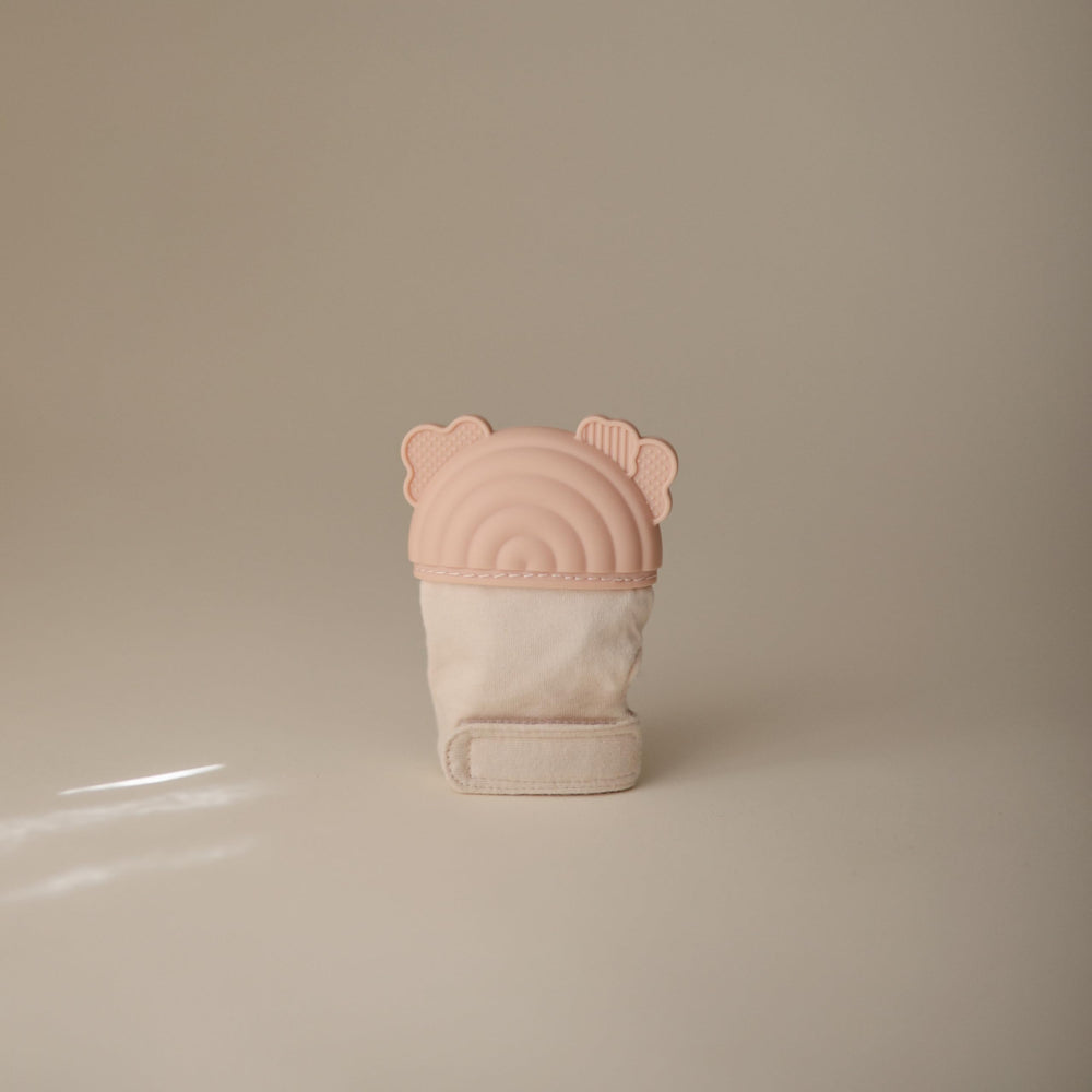 Mushie teething mitten rainbow on hand demonstrates hands-free soothing during playtime.
