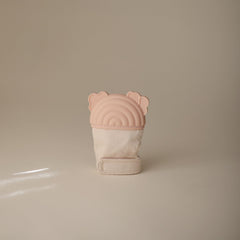 Mushie teething mitten rainbow on hand demonstrates hands-free soothing during playtime.