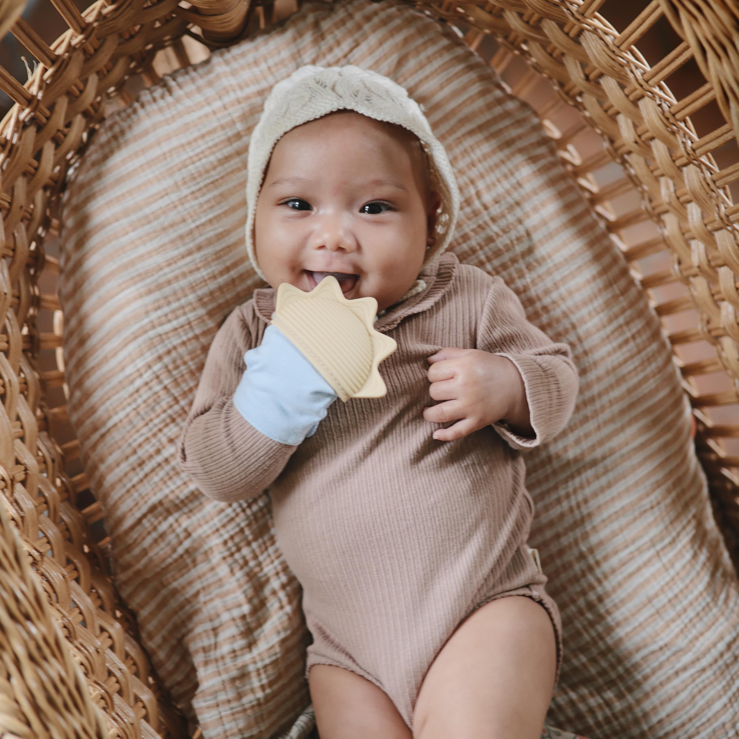 Mushie teething mitten with adjustable strap on a baby wrist