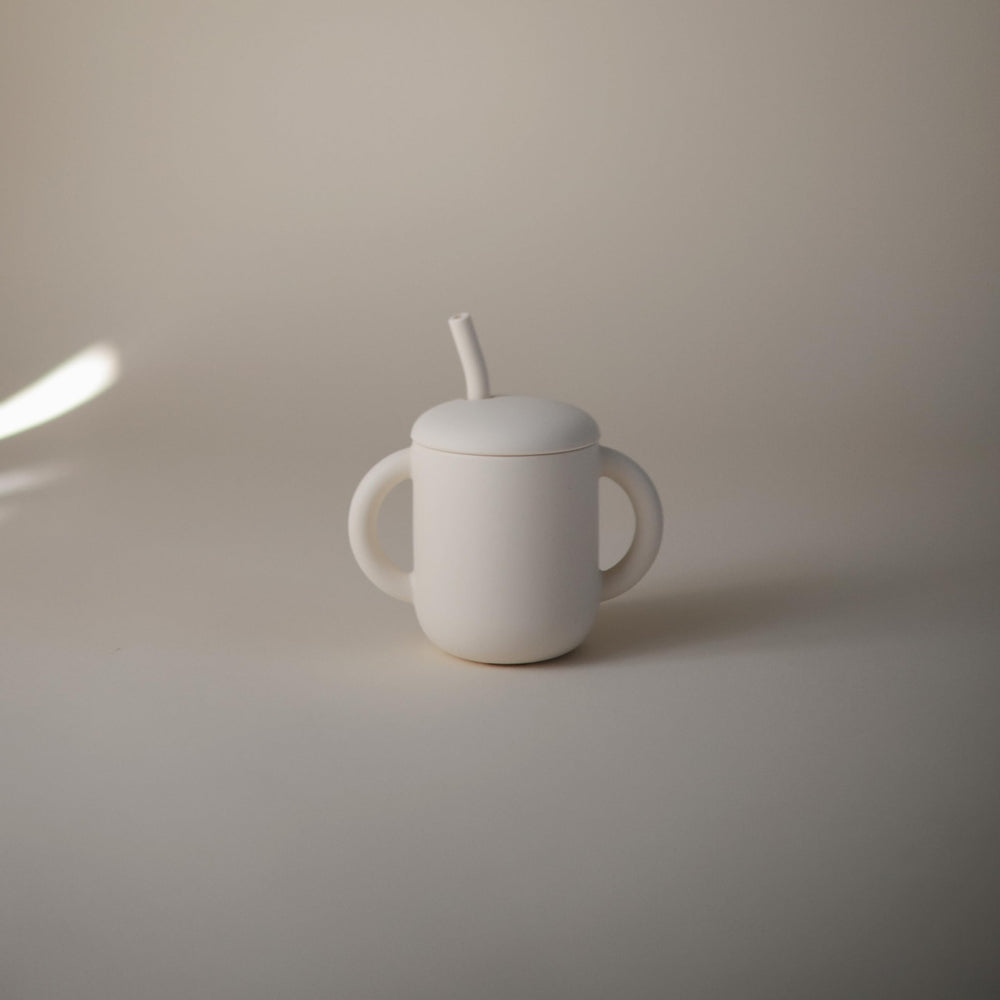 Mushie training cup hands image shows toddler grip to build fine motor skills.