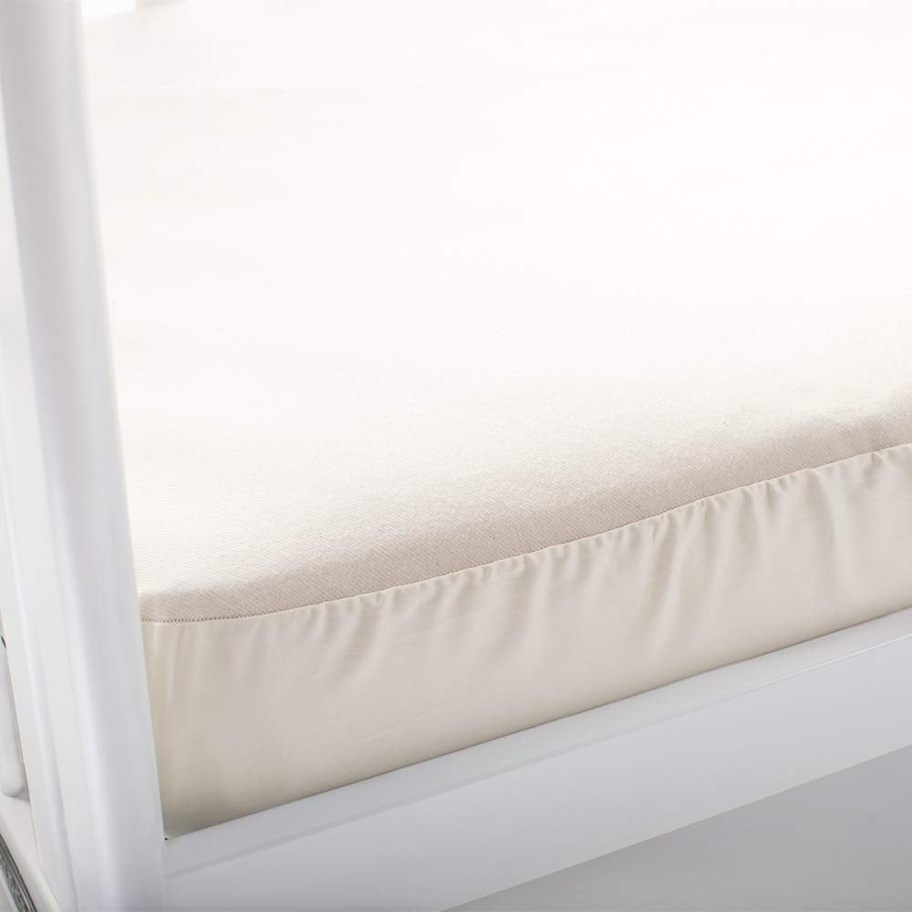 Naturepedic crib mattress pad fitted edges demonstrate secure fit on standard mattresses
