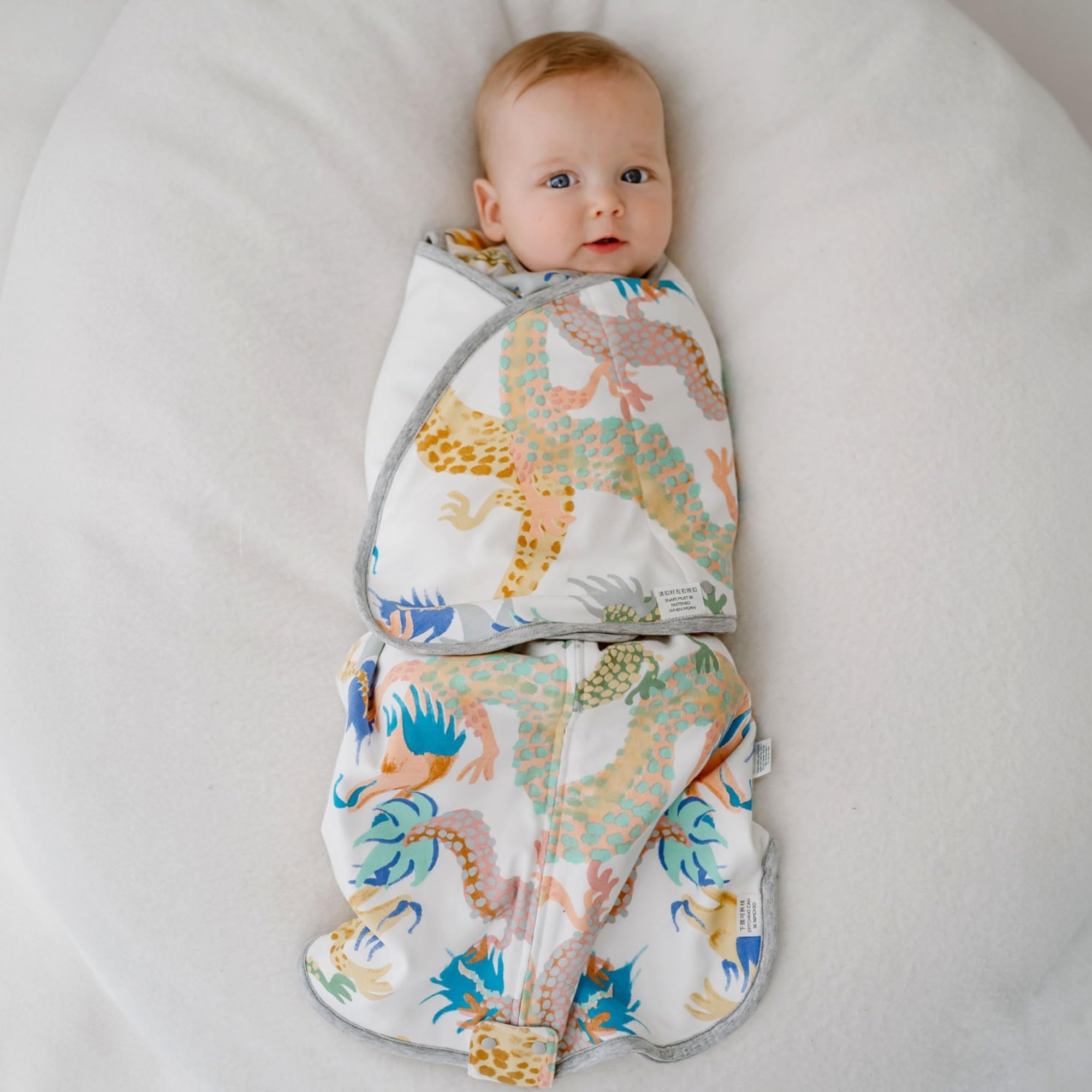 Nest Designs Swaddle Sleep Bag Dragon Dance in-use image shows easy dressing and secure swaddle