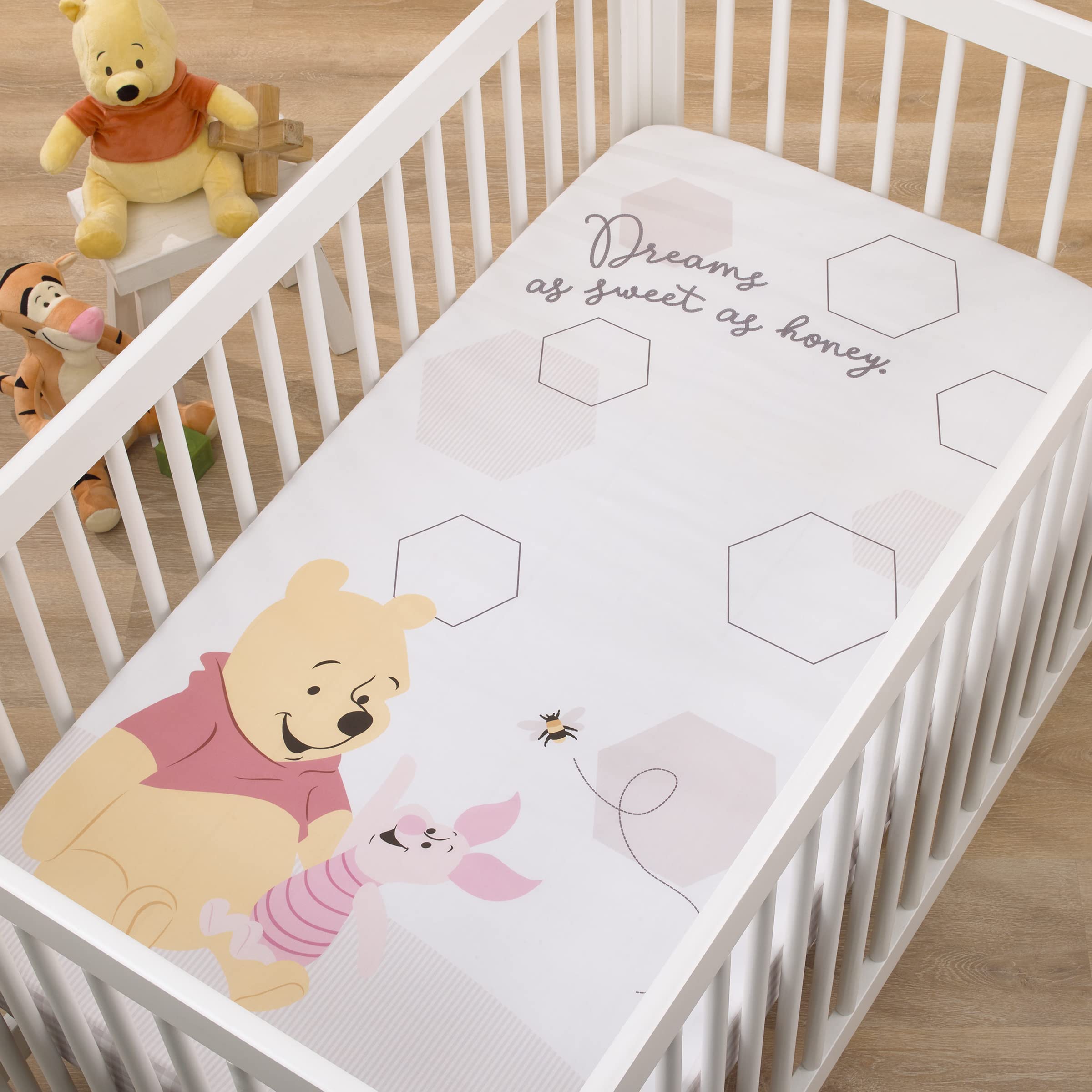 NoJo Disney Pooh Hugs Honeycombs crib sheet on a crib for a photo op