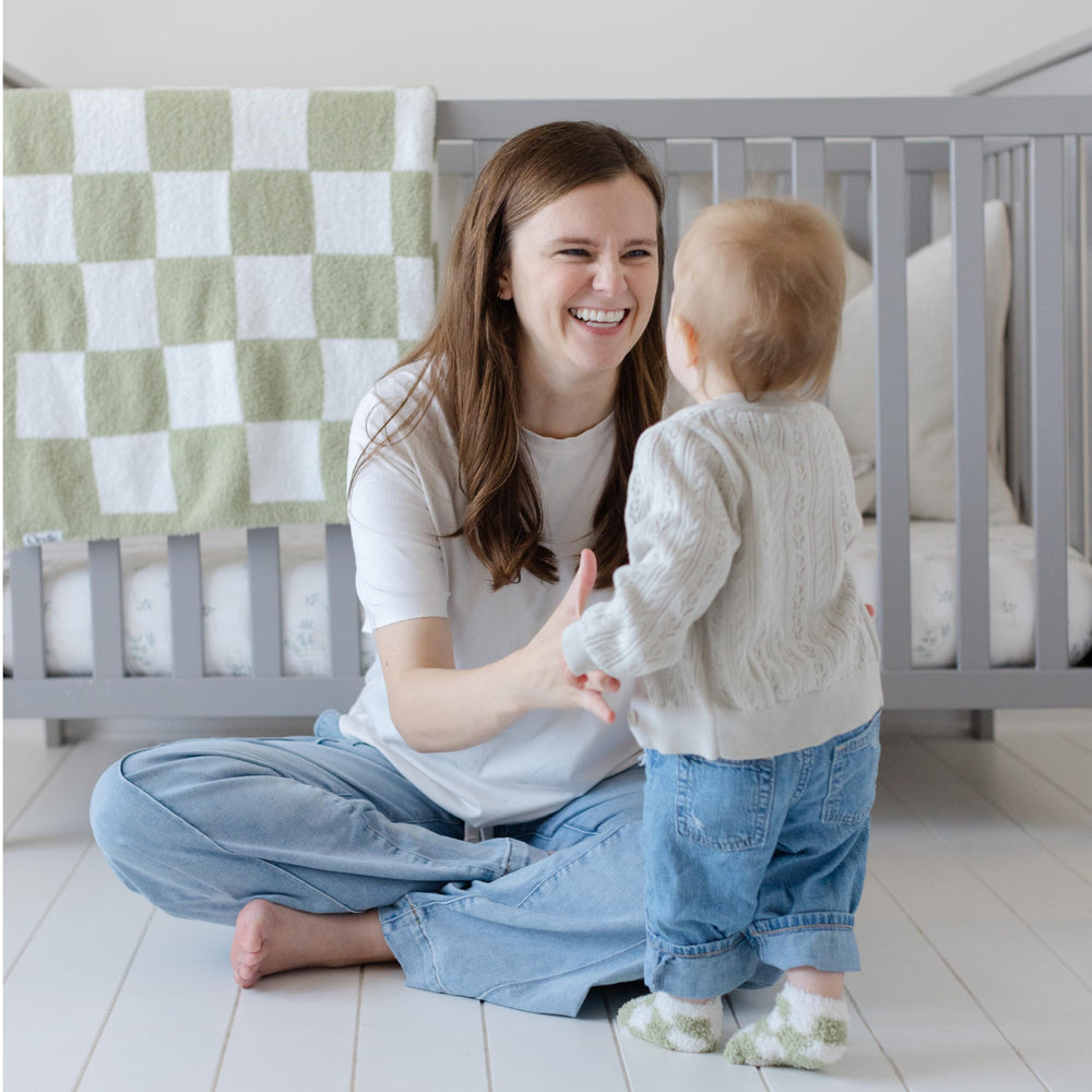 Orelle baby blanket in crib setting—calm, checkered pattern for nursery decor.