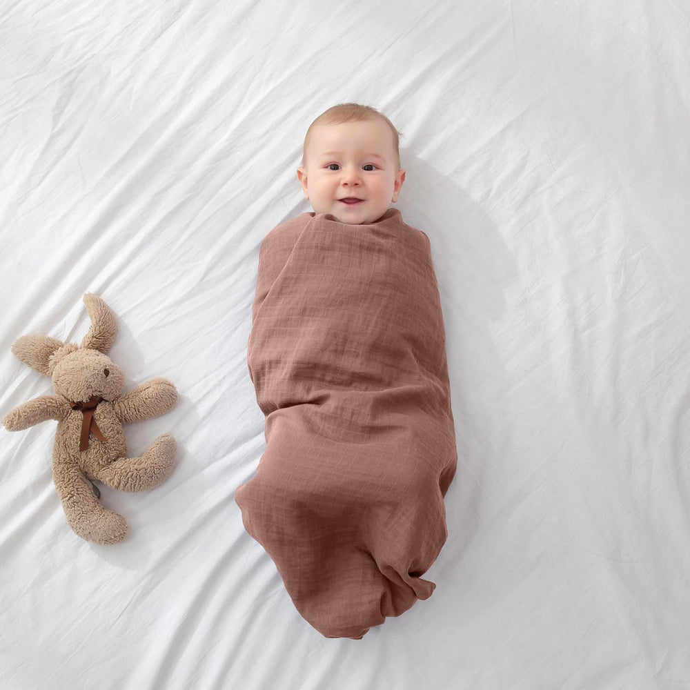 POMISO muslin swaddle blanket closeup soft cotton emphasizes machine-washable durability and colorfast fabric.