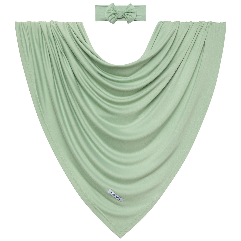 Posh Peanut Sage swaddle setup with baby resting illustrates snug wrap and secure comfort.