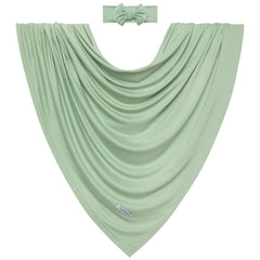 Posh Peanut Sage swaddle setup with baby resting illustrates snug wrap and secure comfort.