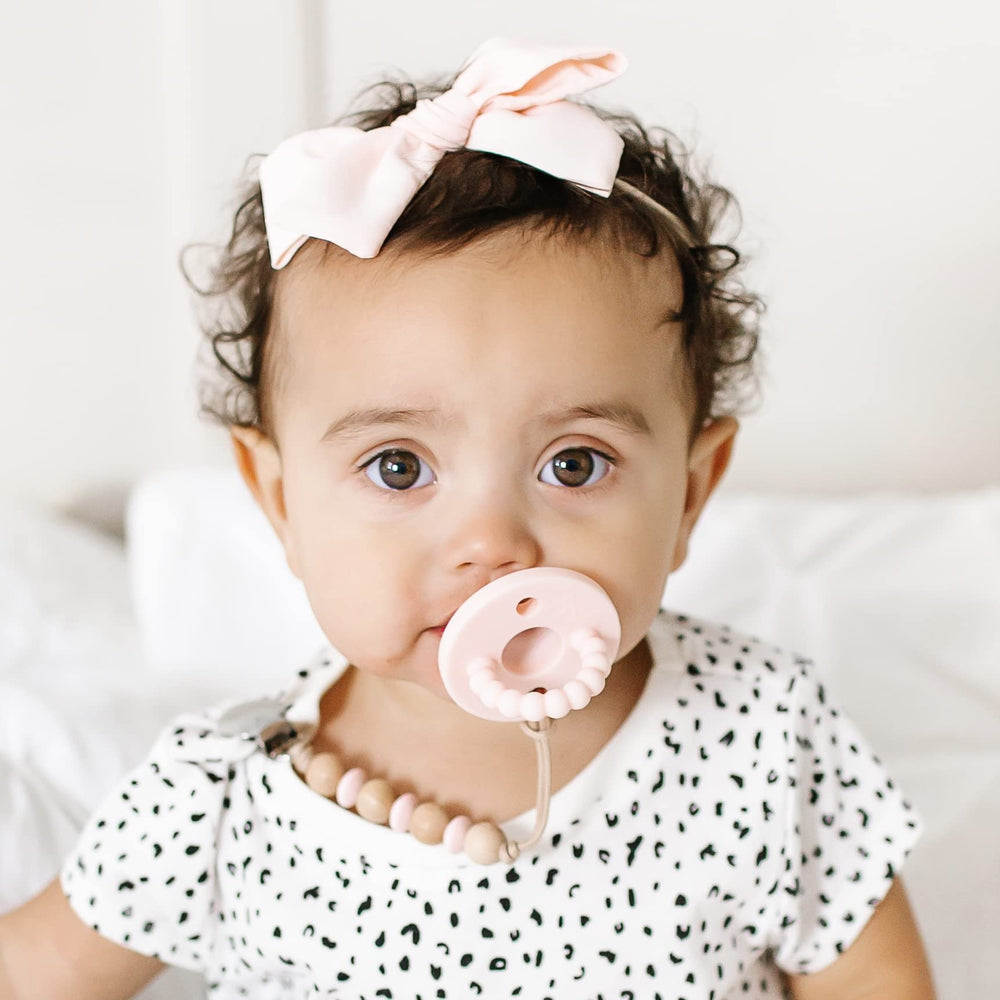 Ryan & Rose Cutie PAT Baby holding pacifier teether supports self-soothing exploration.