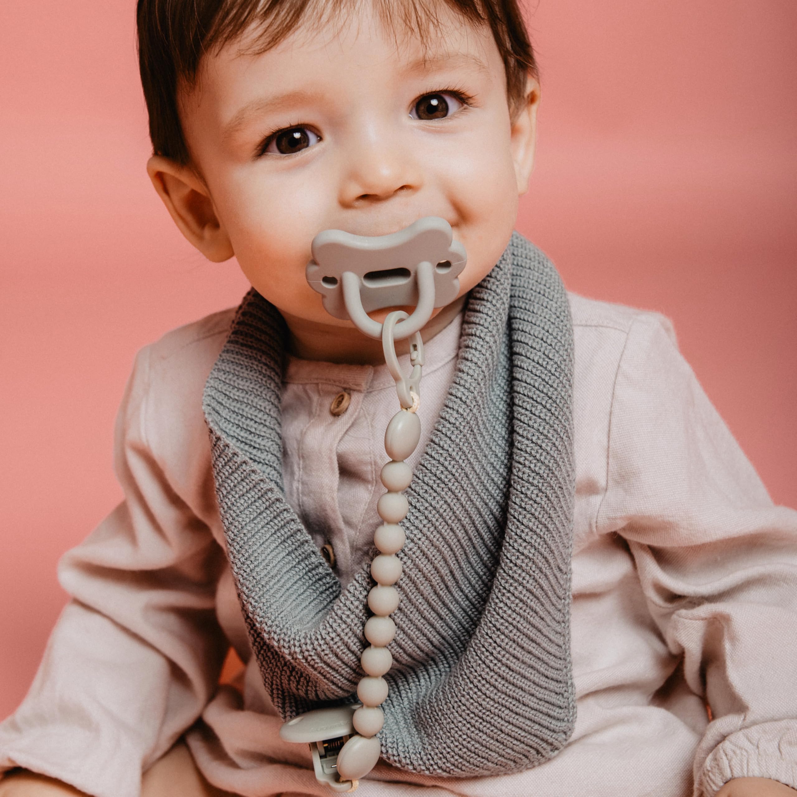 Suavinex green SX PRO pacifier in baby's hand suggests soothing accessibility.