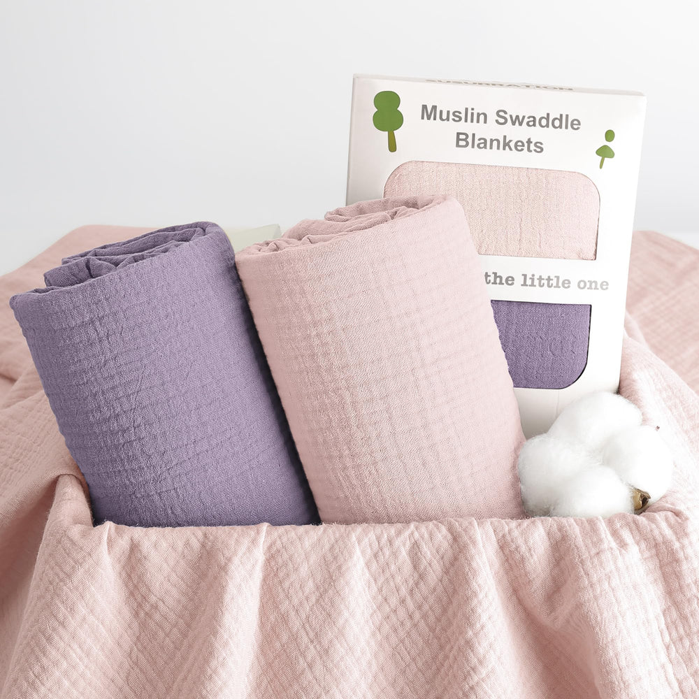 Susurration muslin swaddle blanket pink-purple laid beside packaging demonstrates gift-ready presentation.