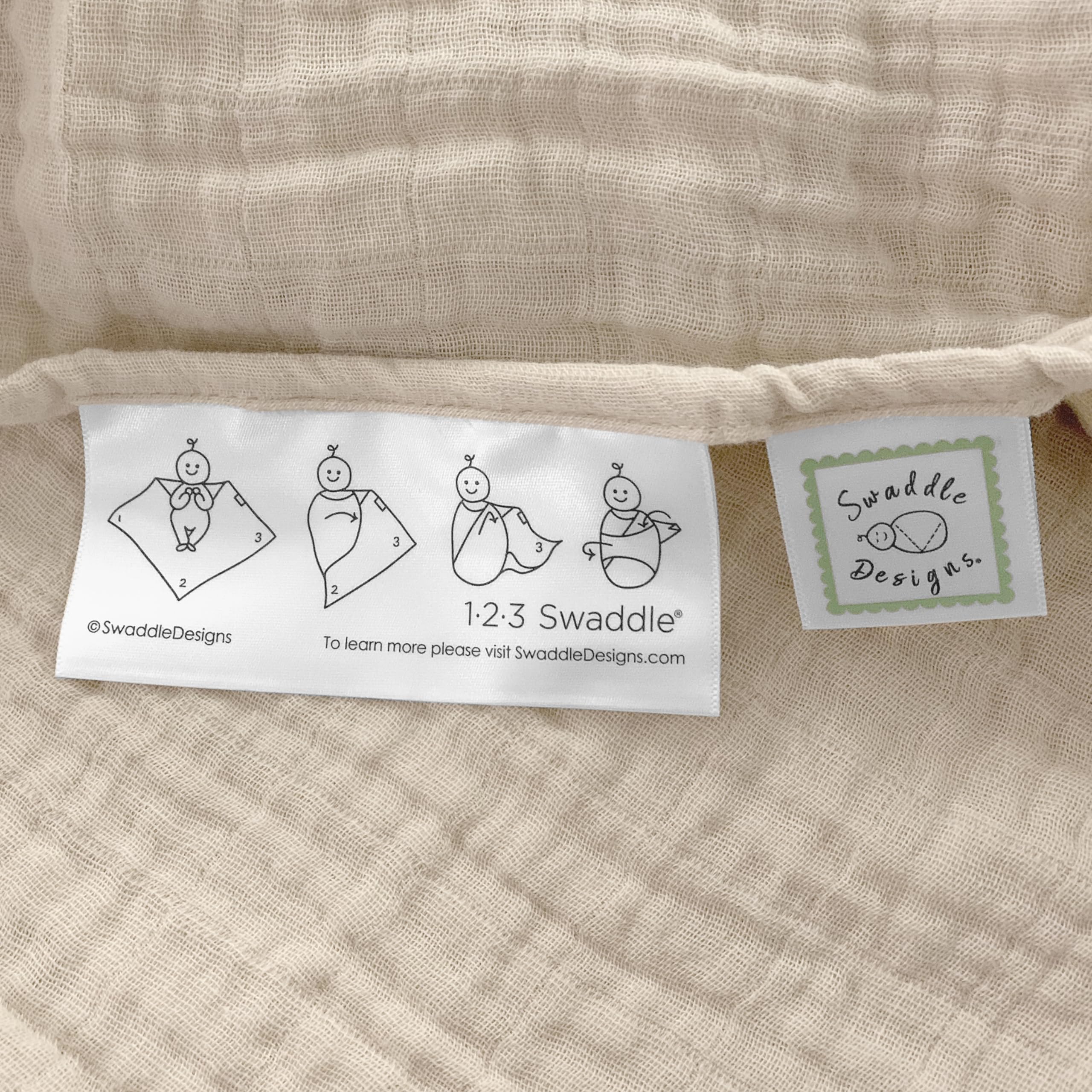 SwaddleDesigns Oceana muslin swaddle blanket on stroller, offering shade and privacy.
