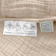 SwaddleDesigns Oceana muslin swaddle blanket on stroller, offering shade and privacy.
