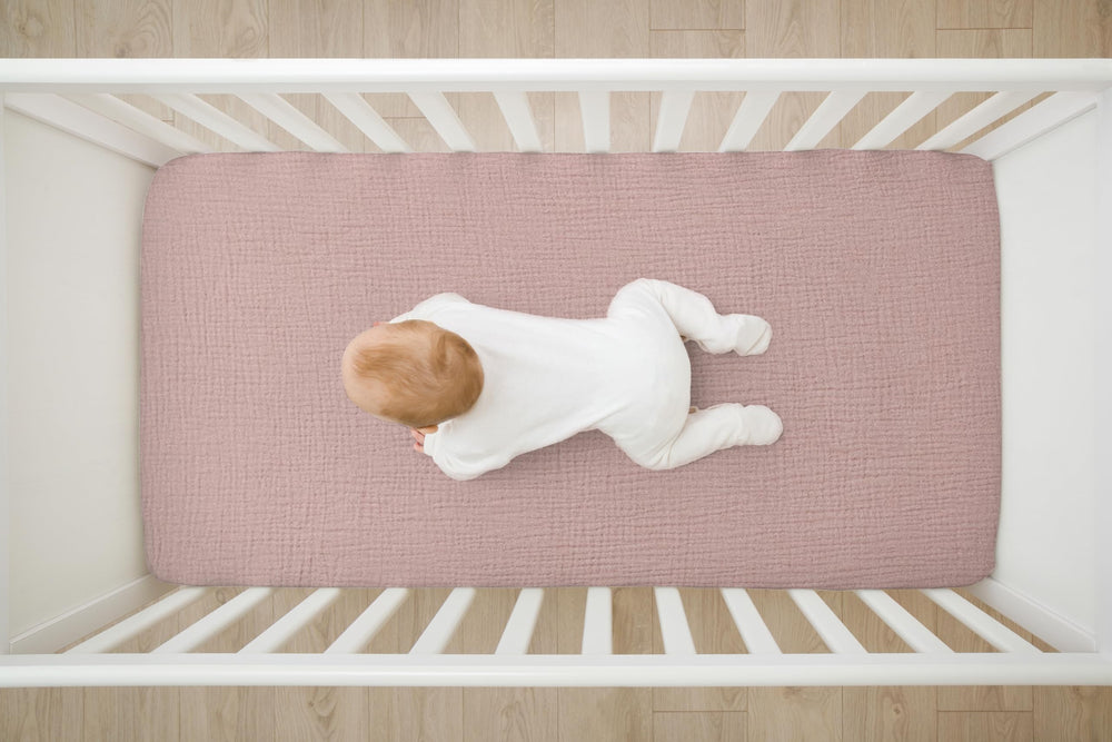 TADO MUSLIN pink-pattern crib sheet on mattress showing deep pockets for secure tuck.