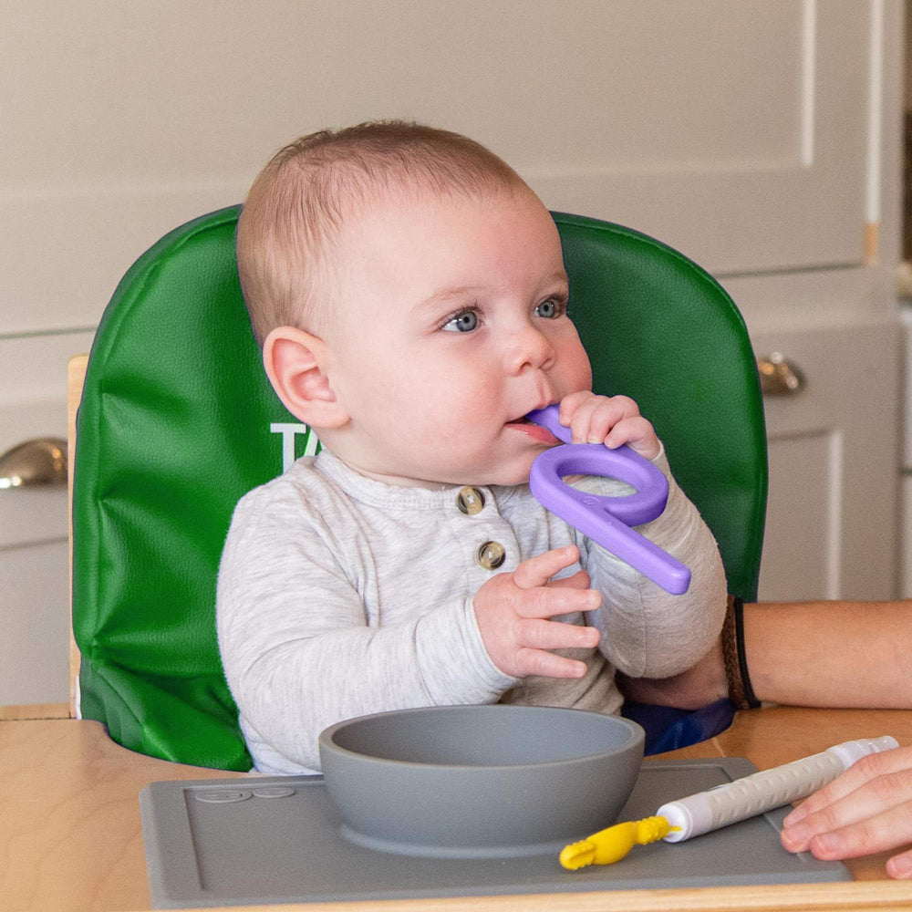 TalkTools High Chair Helper Cushion in use with a toddler, aiding posture during meals.