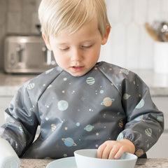 Tiny Twinkle long sleeve bib on child during mealtime demonstrates full-body coverage to protect clothing