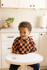 Tiny Twinkle orange bib, side view, demonstrates flexible fit for active toddlers during meals.