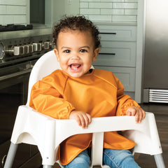 Tiny Twinkle long-sleeve bib sand cinnamon back view highlighting waterproof exterior for quick cleanups.