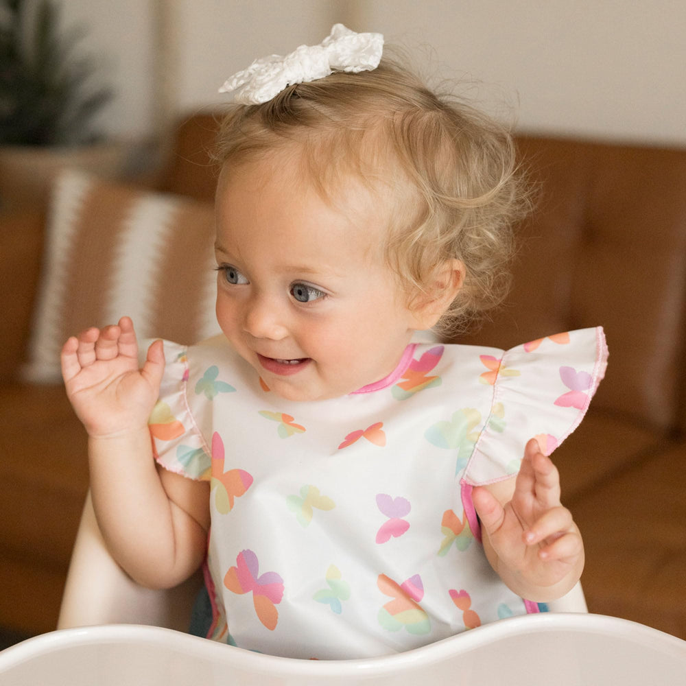 Tiny Twinkle mess-proof bib butterflies worn during mealtime in action demonstrates splash protection.