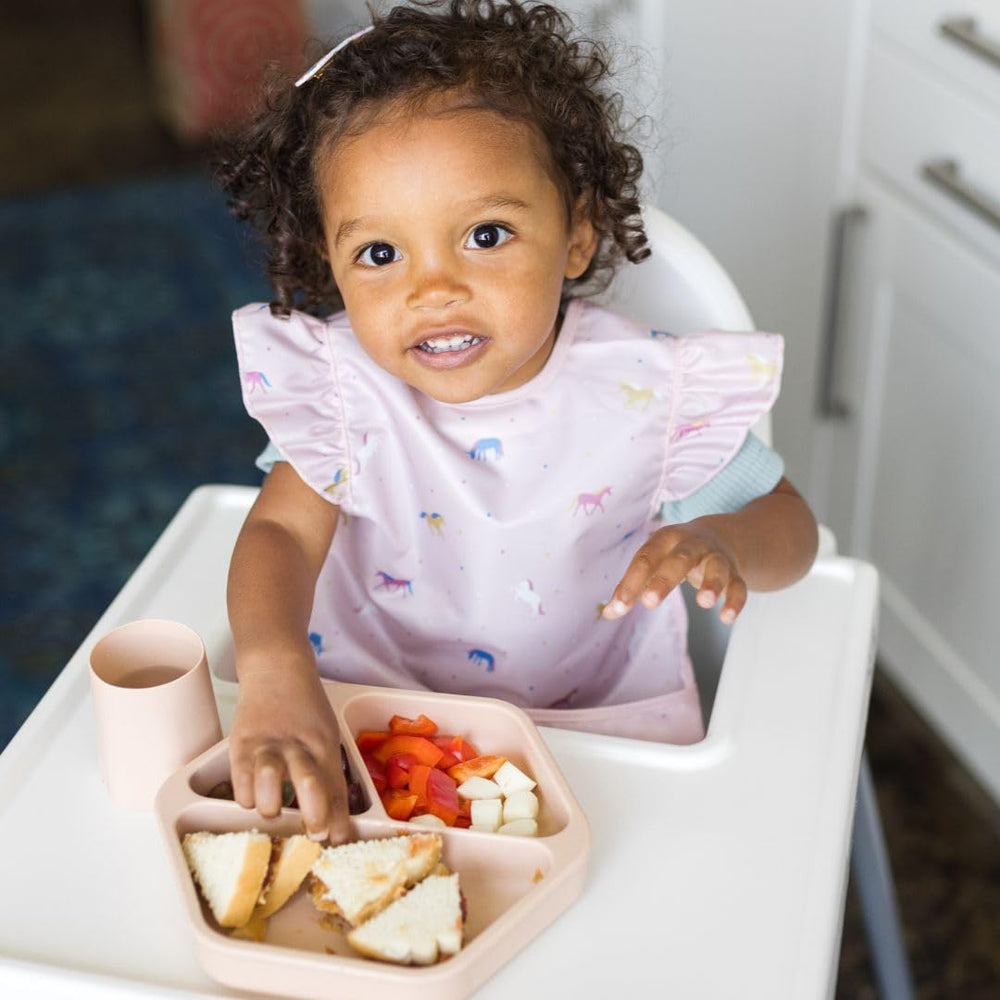 Tiny Twinkle bib on toddler demonstrates flexible, comfortable fit for active mealtimes.