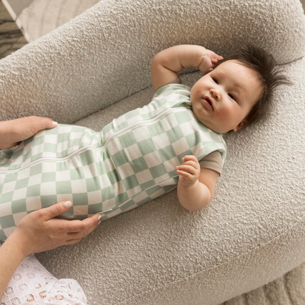 Tiny Twinkle sage checkers baby wearing the sleep sack for cozy sleep.