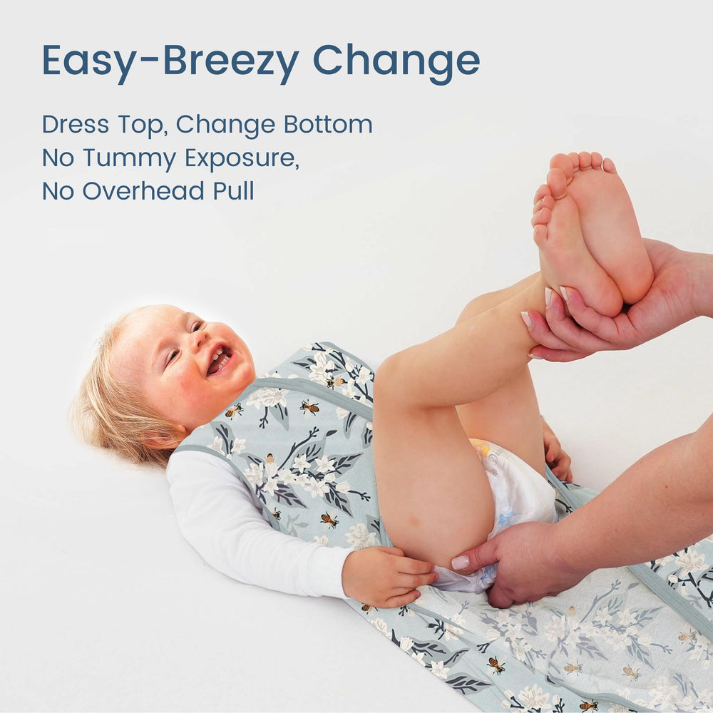 TOTBASIC Bee Floral sleep sack shown in bed supports safe hip movement.