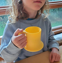 Untippy silicone toddler mug wide-base design reduces tipping on uneven tables.
