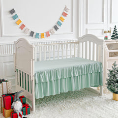 UOZZI BEDDING pom pom trim detail adds playful luxury to the crib.