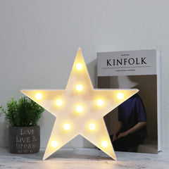 Vicila star sign desk lamp in warm white on a bedside table.