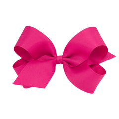 Wee Ones shocking pink bow close-up on WeeStay clip emphasizes secure all-day hold.