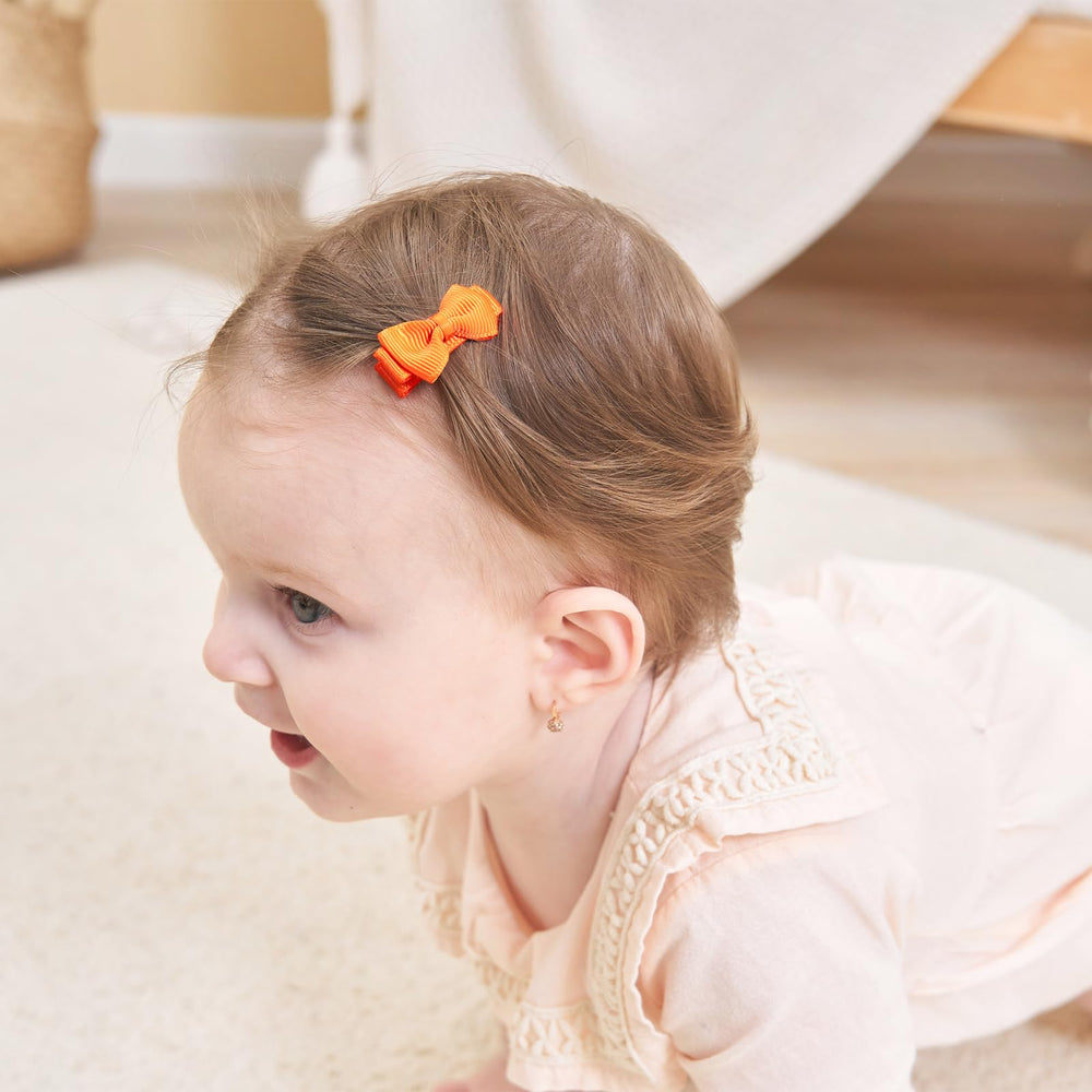 Tiny bows resting in hand show scale and comfort for baby hair