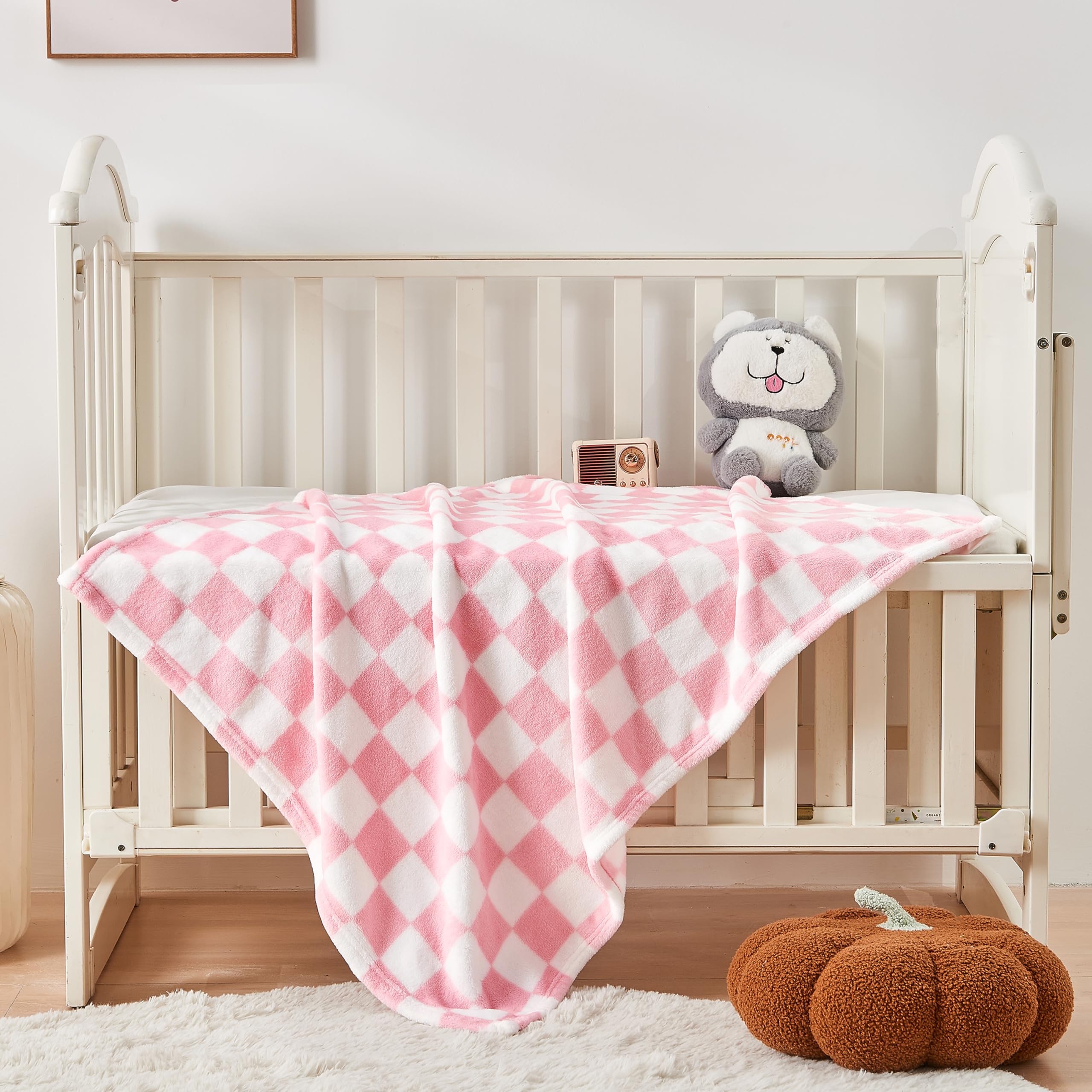 Yurhap pink checkered baby blanket in a nursery scene, adding soft texture and color.